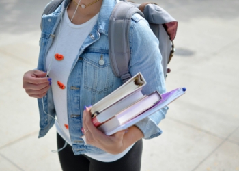woman wearing blue denim jacket holding book