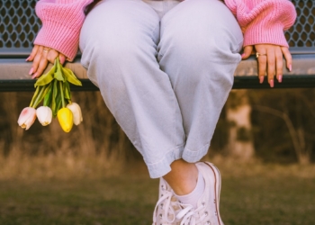 a woman sitting on a bench holding flowers
