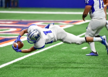 Football player making an incredible diving catch during a high-energy game in the stadium.