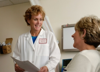 woman in white scrub suit holding gray laptop computer