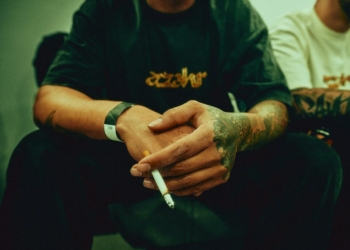 a man sitting down with a cigarette in his hand