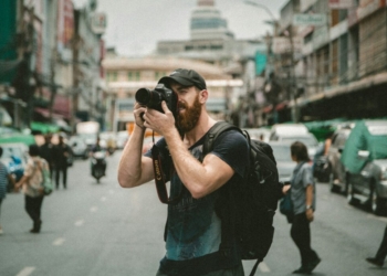 shallow focus photography of man using a DSLR camera
