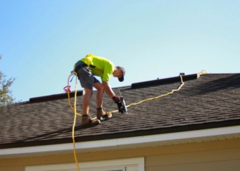 a man working on a roof with a power drill