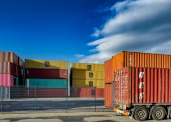 a truck is parked in front of a bunch of shipping containers