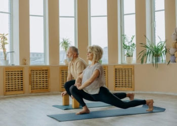 A senior couple practicing yoga indoors, focusing on a healthy lifestyle and flexibility.