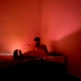 man in red t-shirt sitting on bed