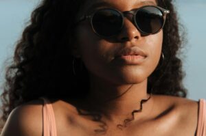 Close-up portrait of a woman wearing sunglasses enjoying a sunny day at the beach.
