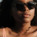 Close-up portrait of a woman wearing sunglasses enjoying a sunny day at the beach.