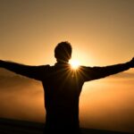 silhouette photo of man on cliff during sunset