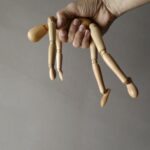 person holding brown wooden mannequin