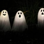 three ghost statues in the dark with their faces glowing