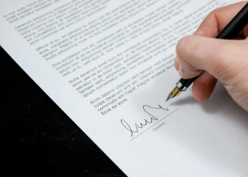 Close-up of a hand signing a formal document with a fountain pen, indicating agreement.