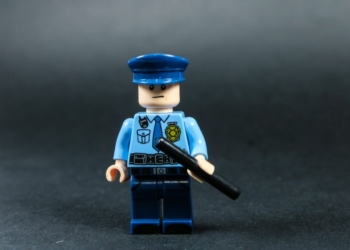 Lego police officer holding a baton against dark background
