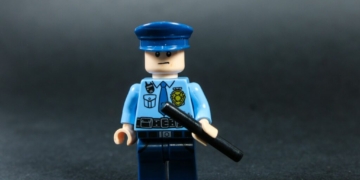 Lego police officer holding a baton against dark background