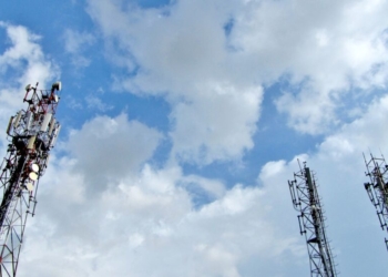 a group of cell towers sitting under a cloudy blue sky