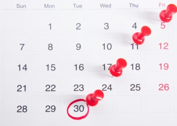 a calendar with red push buttons pinned to it