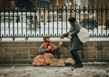 man in black jacket and black pants sitting on white snow covered ground during daytime