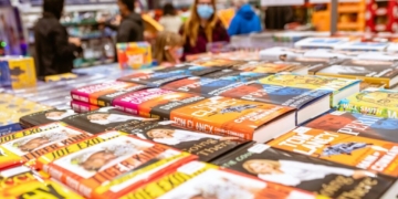 a table full of children's books with people in the background