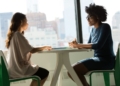 two women sitting beside table and talking