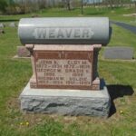 a headstone in the middle of a cemetery