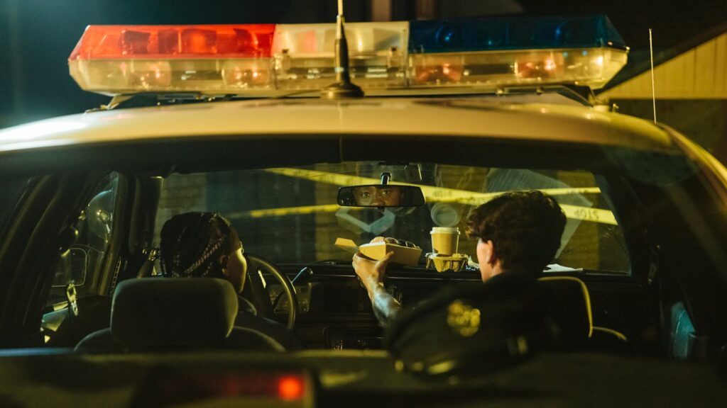 Two police officers eating in their patrol car during a nighttime shift.