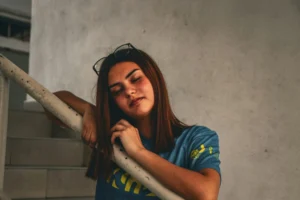 a woman leaning against a railing with her eyes closed
