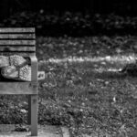 a black and white photo of a person sleeping on a bench