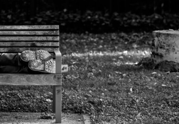 a black and white photo of a person sleeping on a bench