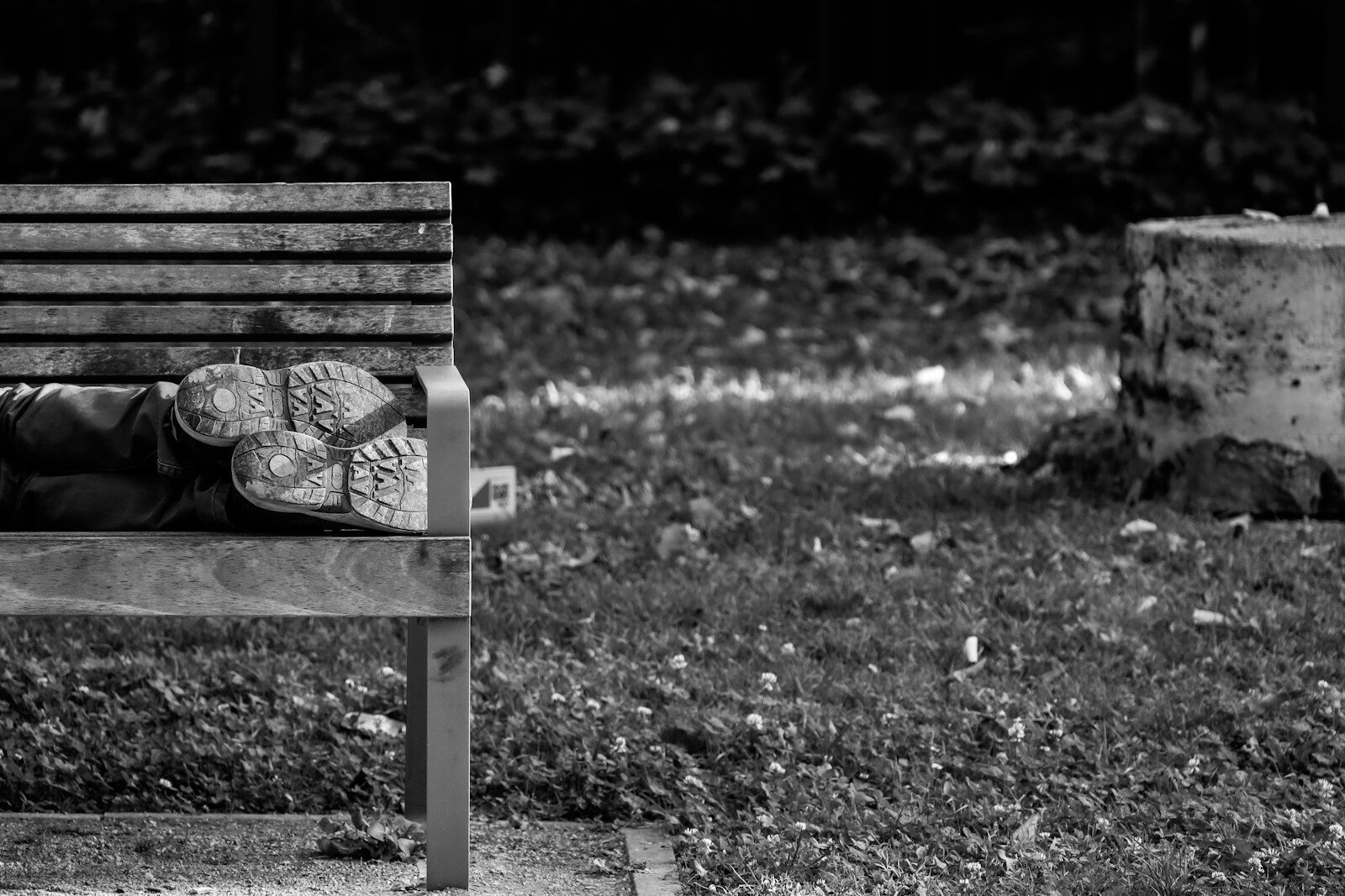 a black and white photo of a person sleeping on a bench