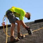 a man working on a roof with a power drill