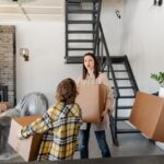 A family carries cardboard boxes into the front hallway of a new Ontario home