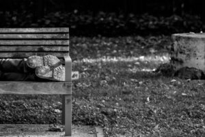 a black and white photo of a person sleeping on a bench