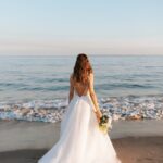 woman in white wedding dress standing on beach during daytime