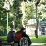 man in black jacket sitting on brown wooden bench during daytime