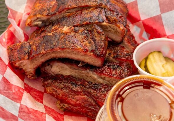Stack of barbecued ribs with pickles and coleslaw