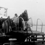People disembarking a ferry onto a pier.