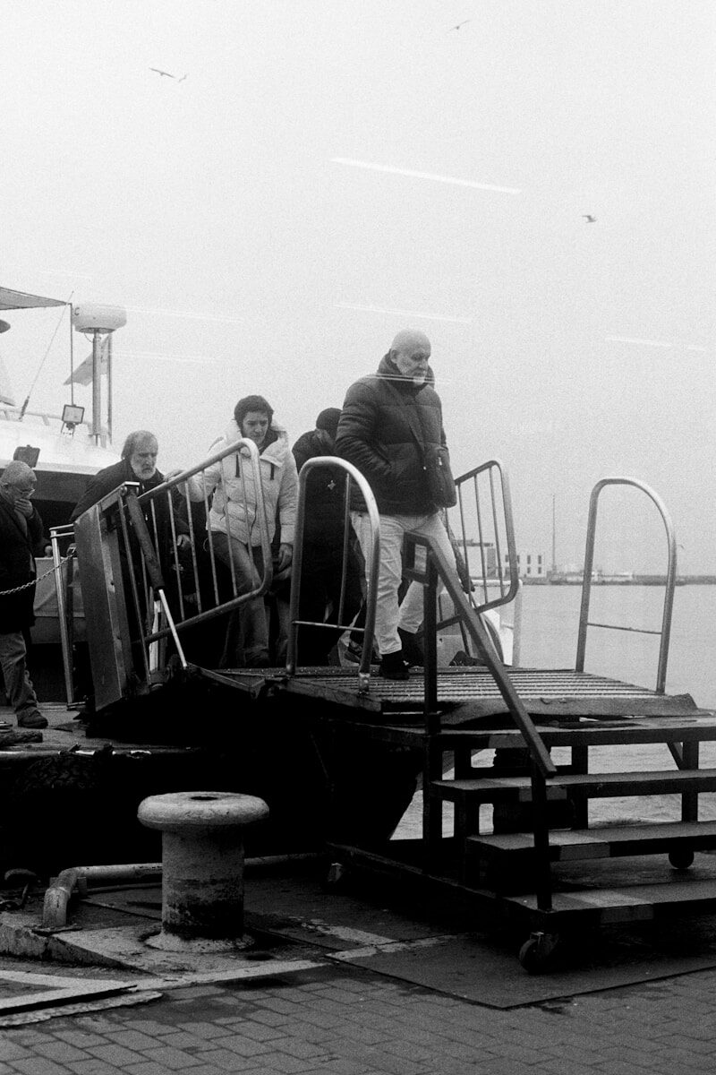 People disembarking a ferry onto a pier.