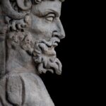 A stone statue of a bearded man in profile.