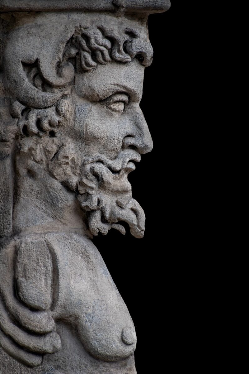 A stone statue of a bearded man in profile.