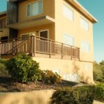 Modern yellow building with wooden balcony and glass details.
