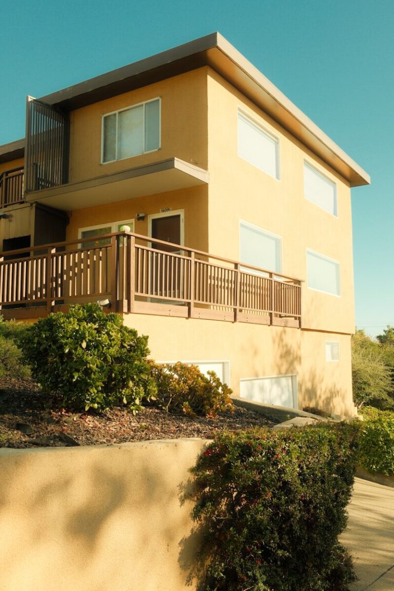 Modern yellow building with wooden balcony and glass details.
