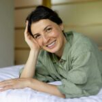 a woman laying on top of a bed next to a laptop computer