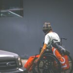 man in white shirt and helmet sitting on orange and black car hood