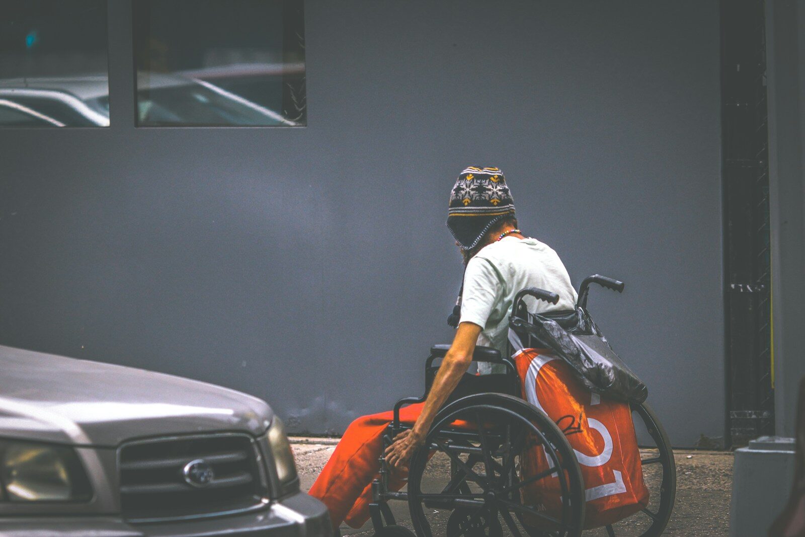 man in white shirt and helmet sitting on orange and black car hood