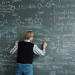 Student writing complex formulas on a chalkboard.