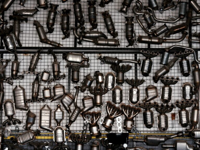 Many catalytic converters hanging on a grid wall.