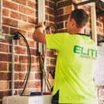 Electrician performing solar battery installation for sustainable energy storage in a home setting.