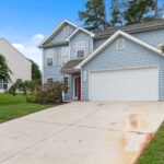 Charming two-story suburban house with spacious driveway and greenery.