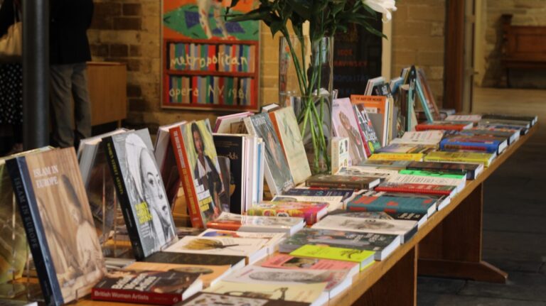A row of books on a table with a vase of flowers