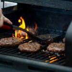 person grilling hamburger patties